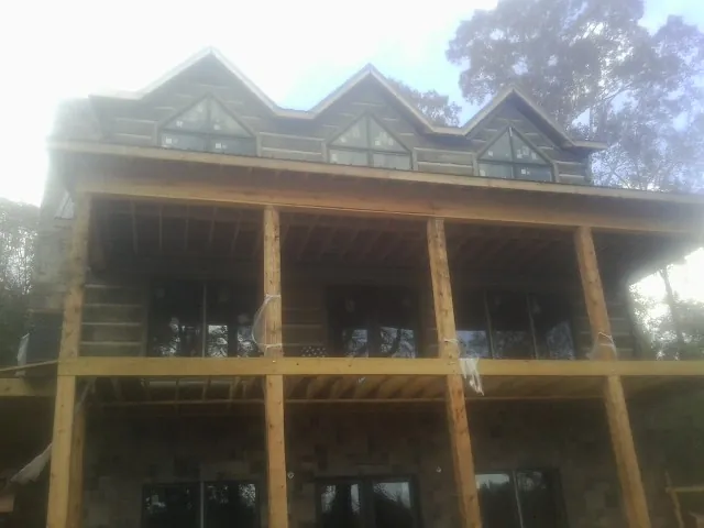 Dormers and porch framing on a large log home under construction — Roof Coating work by our crew in Grandview